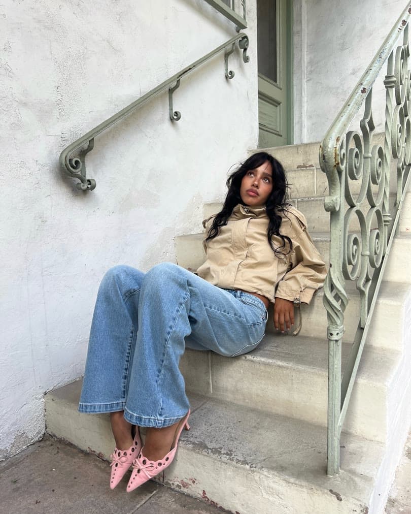 Creator wearing a trench jacket, baggy jeans, and pink heels