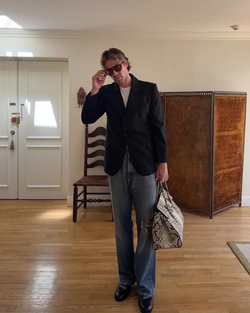 Creator wearing a blazer and washed jeans while carrying a tote